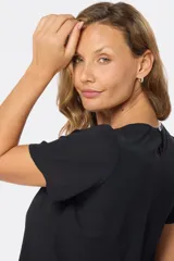 Blusa blanca con estampado floral negro, de corte recto y manga corta.