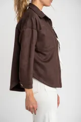 Sobrecamisa de gamuza sintética en color marrón chocolate, con corte oversize, cuello camisero, cierre frontal con botones y bolsillos frontales tipo parche.
