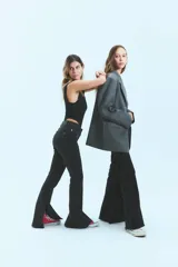 Jean negro de tiro medio alto, corte oxford con botamanga ancha y tajo. Cierre frontal con cinco botones metálicos.