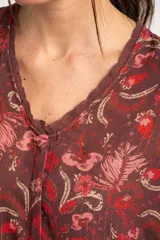Blusa de viscosa color marrón con estampado floral en tonos rosados y rojos, de corte oversize, cuello en V con detalles de encaje y mangas largas abullonadas con inserciones de encaje.