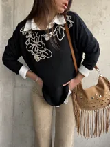 Sweater negro con diseño bordado en hilo crudo en el escote y el hombro, de manga larga y calce holgado.