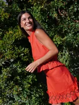 Pollera corta color naranja rojizo, de lino, con volados en el ruedo y detalles de costura en zigzag negra.