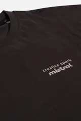 Remera negra de manga corta con corte oversize y cuello redondo. Estampa frontal con la frase "creative spark mistral" en color gris.