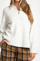 Sweater de punto en color gris melange, con diseño oversize, cuello polo y cierre frontal parcial. Presenta mangas largas y una textura acanalada suave.