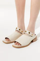 Sandalia de cuero color beige, con diseño slip on y detalle de tachas doradas.