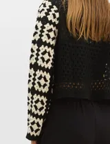 Cardigan abierto de tejido de punto calado con diseño geométrico bicolor en mangas y paneles frontales, y espalda en tono sólido. Presenta silueta recta, frente abierto sin cierre y terminaciones con vivos reforzados en escote, puños y ruedo.