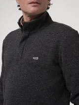 Buzo polar de hombre con medio cierre frontal y cuello alto con aplicación de gamuza. Presenta un tejido con textura de espiga en color gris oscuro y el parche bordado del pato característico de la marca en el pecho.