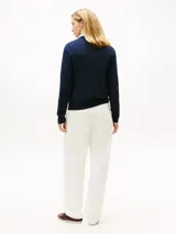 Sweater Tommy Hilfiger de punto trenzado color azul marino, de manga larga con cuello en V y detalles acanalados en puños y dobladillo. Presenta el logo de la marca bordado en el pecho.