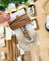 Collar con colgante de nácar circular con agujero central, tiento de cuero marrón y cuentas plateadas.