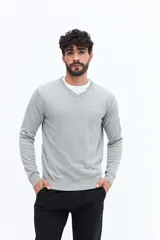 Sweater de punto color gris melange, con escote en V, manga larga y logo bordado en el pecho. Presenta puños y ruedo acanalados.
