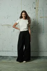 Pantalón de vestir negro de corte ancho y tiro alto, con pinzas frontales y cierre oculto.
