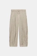 Pantalón de tiro medio con diseño de cuadros vichy en tonos neutros. Presenta pierna ancha, cintura elástica ajustable con cordones, bolsillos laterales y detalle de pinzas en el delantero.