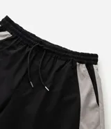 Pantalón barrel de poliéster color negro con recortes contrastantes en tono gris claro en los laterales, de corte amplio y urbano con cintura elástica.
