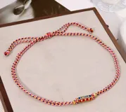 Set de collares cortos con cordones trenzados de múltiples colores y dijes cilíndricos con inscripciones y detalles esmaltados.