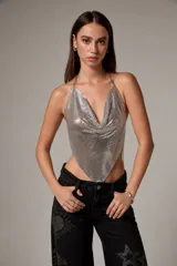 Top halter plateado de malla metálica con escote buche y tirantes de cadena fina.