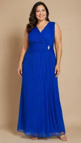 Vestido largo de gasa plisada con destellos de lurex en color azul royal. Presenta escote en V cruzado, sin mangas, con detalle drapeado en la cintura y un broche de strass. Posee una falda larga con tajo frontal.