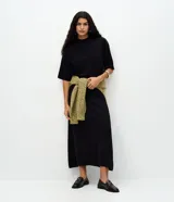 Blusa de punto de corte holgado, color negro, con cuello redondo elevado y mangas cortas amplias con sisa desplazada.