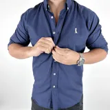 Camisa azul marino a rayas verticales, de corte clásico con cuello italiano y mangas largas con puños abotonados.