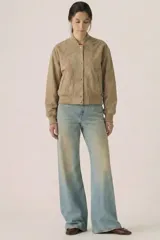 Campera tipo bomber cropped de gamuza sintética color beige, con cuello, puños y ruedo de rib elástico. Cuenta con bolsillos laterales ribeteados y cierre frontal con botones a presión metálicos.