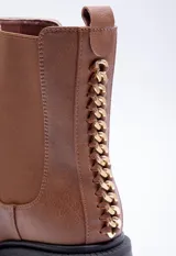 Bota de caña media color marrón con pieza elastizada en los laterales, detalle metálico atrás y plataforma de 6cm de alto.