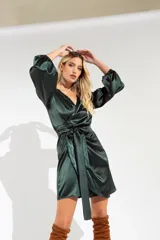 Vestido corto color verde esmeralda de satén, con escote cruzado, mangas largas abullonadas con puños elásticos y lazo en la cintura.