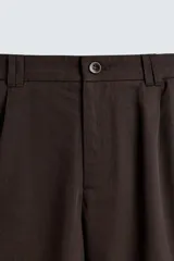 Bermuda de corte regular fit color marrón oscuro, confeccionada en tejido de lyocell y algodón. Presenta bolsillos cargo con solapa en las perneras, bolsillos delanteros y bolsillos traseros de vivo. Cierre frontal con cremallera y botón.