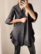 Camisa negra de tejido suave tipo seda, con manga tres cuartos y volados irregulares en mangas y ruedo.