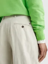 Pantalón de algodón elástico color crema con estampado integral de monogramas TH tonales en jacquard. Tiene dos bolsillos abiertos en la cadera y dos bolsillos traseros con botón.