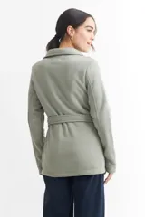 Tapado negro de poliéster con cuello solapa, doble botonadura, cinturón y bolsillos laterales.