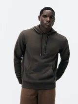 Buzo con capucha de corte clásico, confeccionado en tejido de algodón, con bolsillo frontal tipo canguro y puños acanalados.