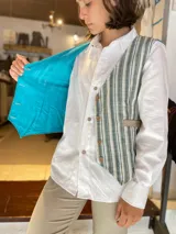 Chaleco reversible de lino, color naranja en el exterior y rayas finas en el interior, con cuello en V y cierre frontal de botones.