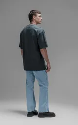 Remera de corte relajado y silueta amplia, con hombros caídos y mangas cortas. Confeccionada en algodón premium, presenta un diseño liso en color gris oscuro.