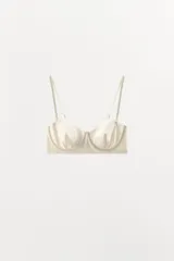 Sujetador de color blanco hueso o crema, con aros y copas moldeadas, corte recto en el bajo y tirantes finos ajustables y extraíbles.