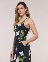 Vestido midi evasé de algodón color negro con estampado floral blanco y verde, de la marca Julia Jordan. Presenta escote recto, breteles anchos y espalda en punto smock. Incluye bolsillos laterales y forro interior de poliéster.