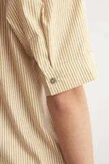 Camisa de manga corta color beige con sutiles rayas verticales blancas, cuello mao y cierre frontal oculto con botones.