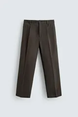 Pantalón relaxed fit de traje color marrón oscuro, confeccionado en tejido con mezcla de algodón. Cuenta con bolsillos frontales, bolsillos traseros de doble vivo con botón y efecto lavado. Cierre frontal con cremallera y botón.