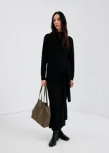 Chaleco negro de punto, de corte recto y largo, con cuello alto.