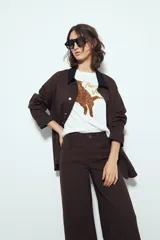 Pantalón de pierna amplia color beige, con silueta relajada y calce cómodo, confeccionado en denim con leve elasticidad. Presenta costuras a contraste.