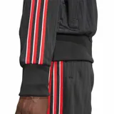 Campera deportiva Adidas modelo Firebird Pinstripes, de color negro con sutiles rayas verticales y detalles de tiras rojas y blancas en las mangas. Cuenta con cuello alto, cierre frontal completo y el logo del trifolio bordado en el pecho.