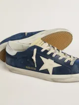 Zapatillas urbanas Golden Goose modelo Super-Star, color azul con efecto desgastado, estrella blanca en el lateral, talón plateado y cordones blancos.