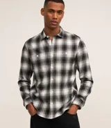 Camisa de franela a cuadros en blanco y negro, de corte comfort, con cuello inglés, abotonadura frontal, manga larga, bolsillo en el pecho y puños abotonados.