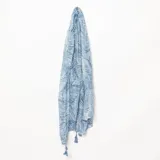 Pashmina de tela ligera con estampado de hojas en tonos azul y blanco, terminada con flecos en los extremos.