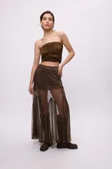 Falda larga transparente color marrón con hilos dorados, con goudets que generan vuelo y costuras desflecadas. Incluye un short corto debajo.
