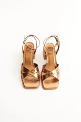 Sandalias de mujer color bronce metálico, con tiras cruzadas en el empeine, punta cuadrada y taco ancho de altura media. Cuentan con tira fina ajustable al tobillo.
