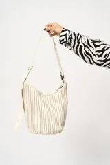 Cartera tipo hobo color crema con diseño plisado y correa de hombro ajustable.