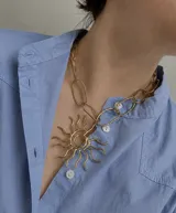 Collar de bronce con cadena de eslabones ovalados y un gran dije colgante con diseño de sol y rayos ondulados.