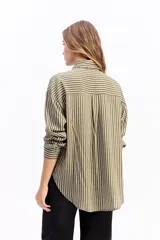 Camisa de manga larga con estampado de rayas verticales en tonos azul y blanco. Presenta cuello clásico, cierre frontal con botones y dos bolsillos tipo cargo en el pecho. Su diseño es de corte relajado y holgado.