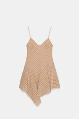 Vestido corto con escote en V y tirantes finos ajustables, confeccionado en tejido a cuadros beige y rojo. La falda es asimétrica y presenta un bajo con detalle de encaje.