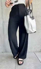 Pantalón negro de lino de corte holgado, con cintura alta y cierre con doble botón.