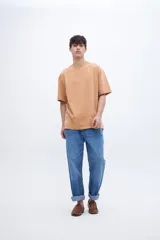 Remera de algodón pesado con calce oversize, cuello redondo con detalle de costura en V y tajos laterales en el ruedo, con un largo posterior ligeramente mayor al delantero.